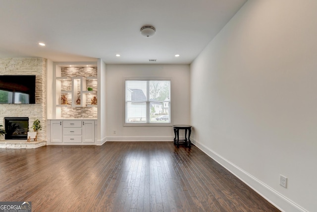unfurnished living room featuring a stone fireplace, visible vents, baseboards, recessed lighting, and dark wood-type flooring