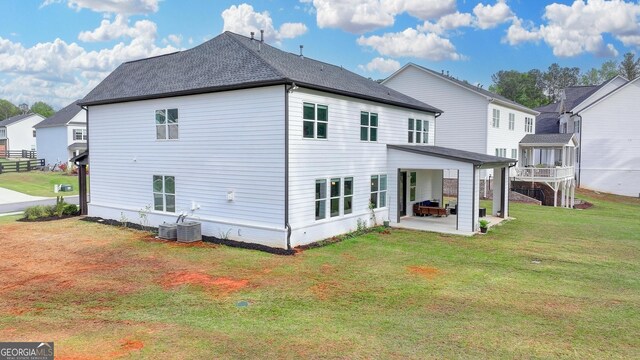 back of property featuring a patio, a shingled roof, and a yard