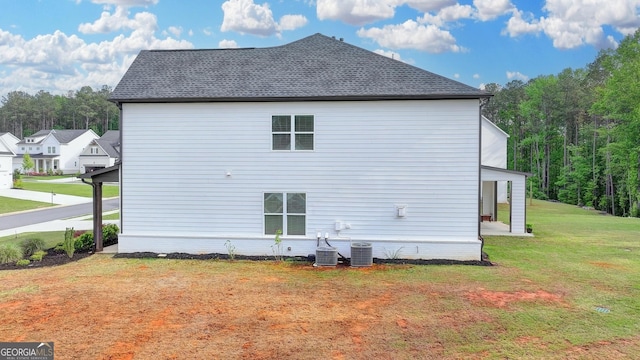 rear view of property with a lawn, central AC, and a wooded view