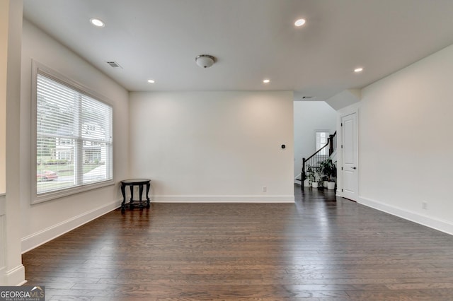 unfurnished living room featuring recessed lighting, dark wood finished floors, and stairs