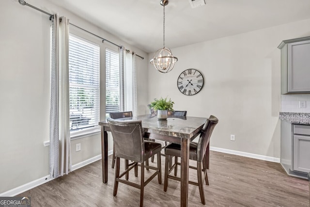 dining area featuring baseboards, wood finished floors, and a notable chandelier