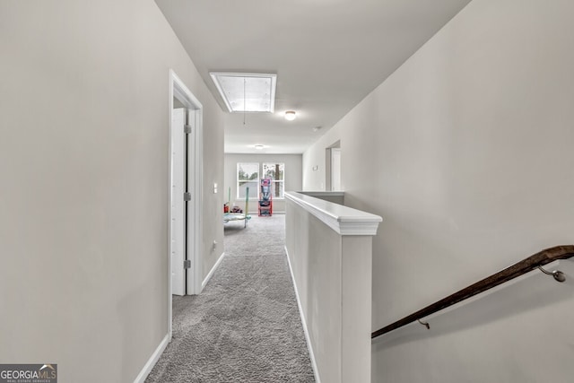 hallway featuring baseboards, attic access, an upstairs landing, and light carpet
