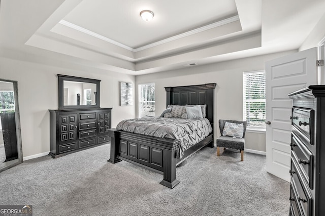 carpeted bedroom featuring multiple windows, ornamental molding, and a tray ceiling