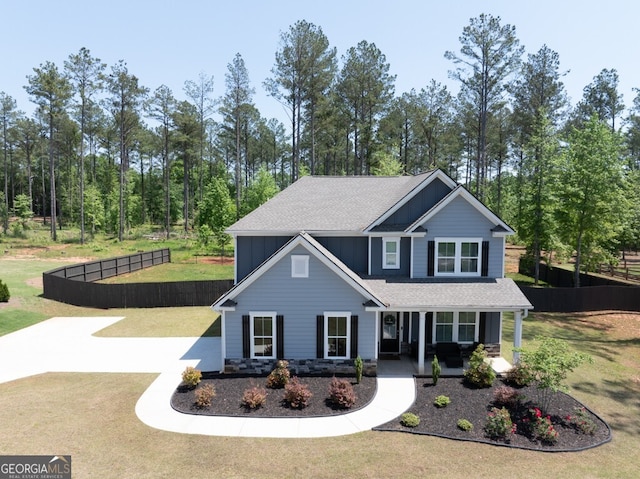 view of front of property with board and batten siding, covered porch, roof with shingles, fence, and a front lawn