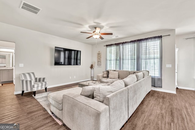 living area featuring a ceiling fan, baseboards, visible vents, and wood finished floors