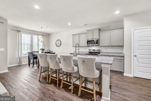 233 Jim Daws Rd, Monroe, GA 30655 - kitchen with stainless steel appliances, gray cabinets, a kitchen island with sink, a kitchen bar, and dark wood-type flooring
