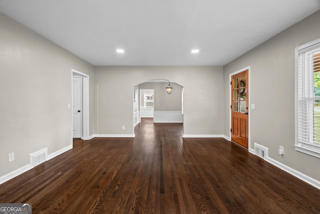 interior space featuring visible vents, arched walkways, dark wood-type flooring, and recessed lighting