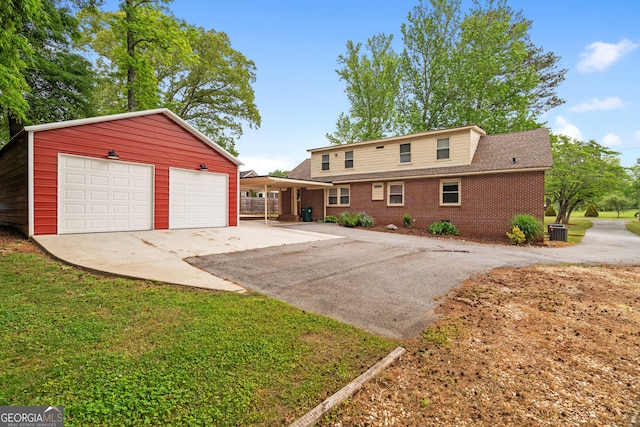 view of front of home featuring a detached garage, an outdoor structure, central AC, and brick siding