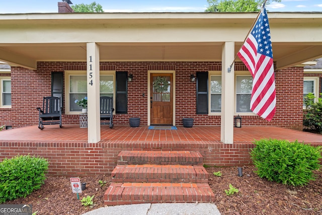 property entrance featuring a porch and brick siding