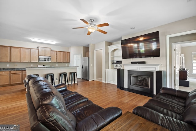 1355 Hesse Ln, Austell, GA 30106 - living area featuring light wood-type flooring, a ceiling fan, a fireplace with flush hearth, and baseboards
