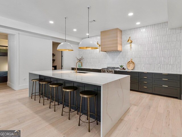 650 Jones Rd, Roswell, GA 30075 - kitchen featuring a sink, decorative backsplash, light wood-style floors, and light stone countertops