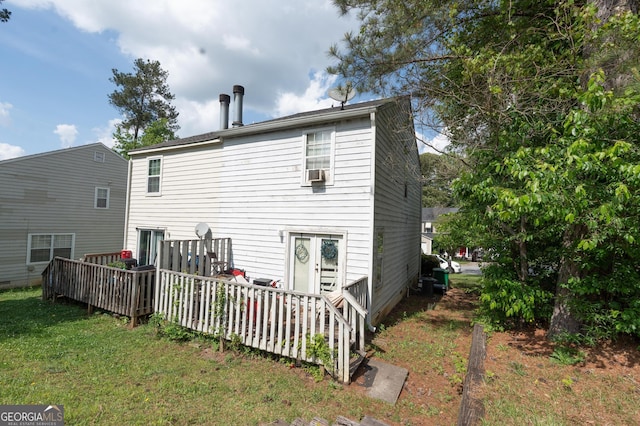rear view of property with a lawn, a deck, and cooling unit