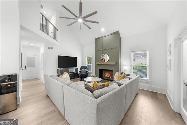 living area featuring high vaulted ceiling, a ceiling fan, light wood finished floors, and visible vents