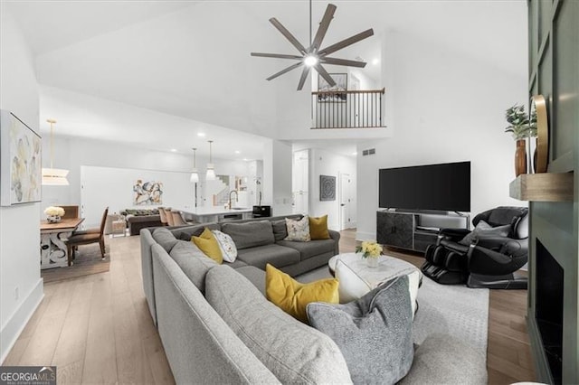 living area featuring high vaulted ceiling, baseboards, a ceiling fan, and light wood-type flooring