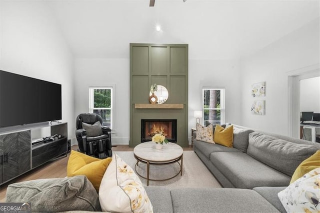 living area with high vaulted ceiling, a large fireplace, and wood finished floors