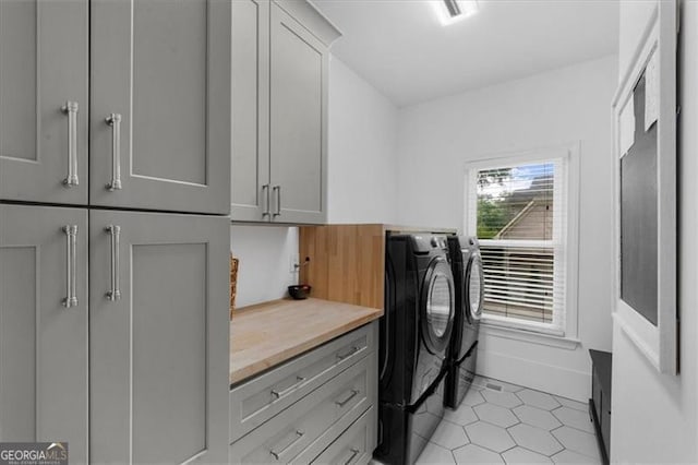 washroom with washer and clothes dryer, cabinet space, and light tile patterned floors