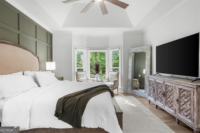 bedroom featuring ceiling fan, ornamental molding, wood finished floors, and a raised ceiling