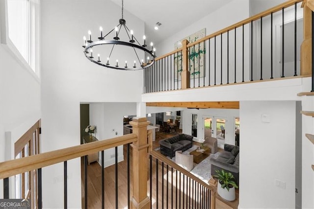 interior space with french doors, a towering ceiling, wood finished floors, and a chandelier