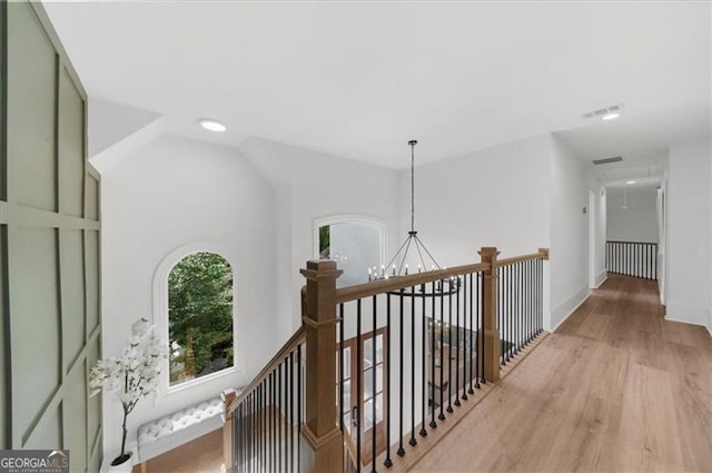 hallway featuring an inviting chandelier, attic access, recessed lighting, light wood-style flooring, and an upstairs landing