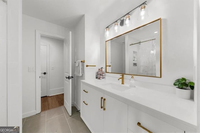 bathroom featuring tile patterned floors, walk in shower, baseboards, and vanity