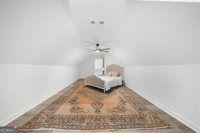 bedroom with visible vents, wood finished floors, baseboards, a ceiling fan, and vaulted ceiling
