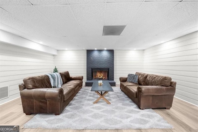 living room featuring wooden walls, a fireplace, wood finished floors, and visible vents