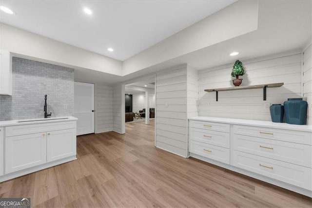 interior space featuring recessed lighting, decorative backsplash, a sink, and light wood finished floors