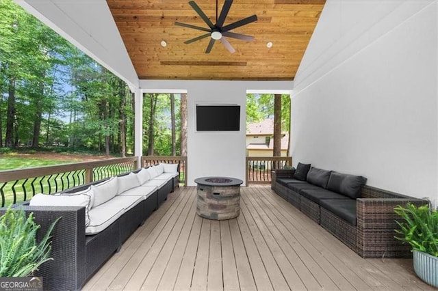 wooden terrace with a ceiling fan and an outdoor living space with a fire pit
