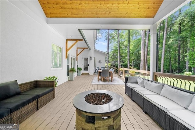 sunroom featuring an outdoor living space with a fire pit and outdoor dining area