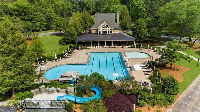 pool with a patio area and a wooded view