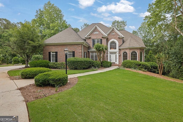 colonial inspired home with brick siding and a front yard