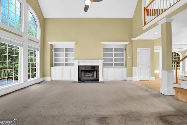 unfurnished living room with high vaulted ceiling, a ceiling fan, a fireplace, carpet flooring, and baseboards