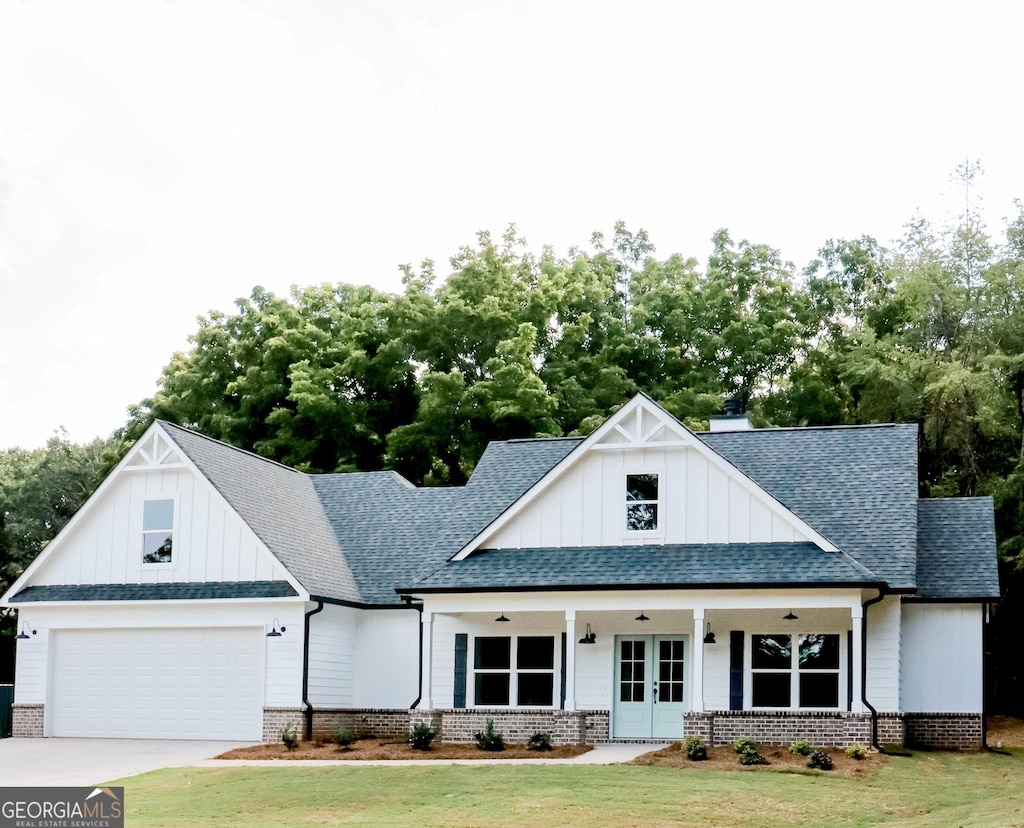 modern farmhouse style home featuring a front lawn, roof with shingles, and french doors