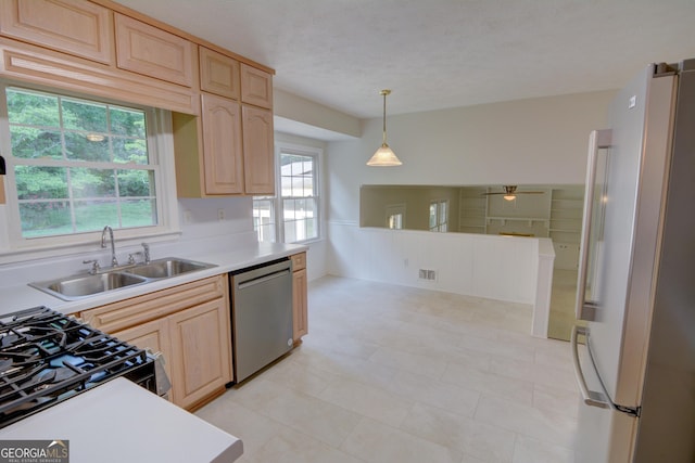kitchen with stainless steel dishwasher, freestanding refrigerator, a sink, and light brown cabinetry