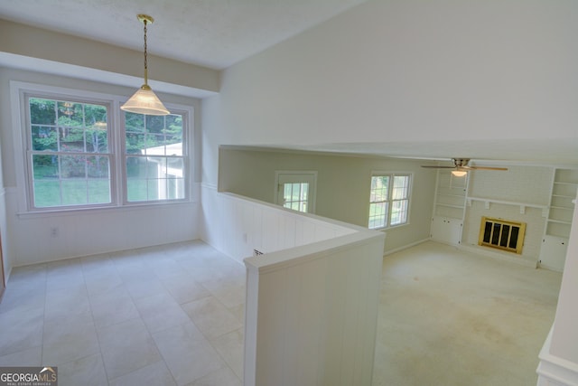 interior space with a wainscoted wall, ceiling fan, and a fireplace