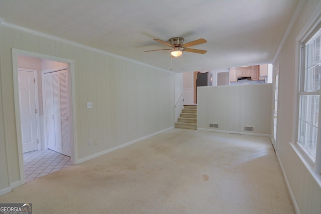 unfurnished room featuring ceiling fan, ornamental molding, light colored carpet, and visible vents
