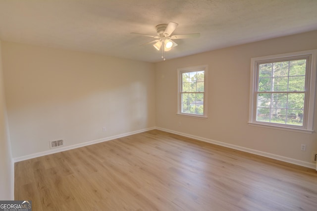 unfurnished room with baseboards, ceiling fan, light wood finished floors, and visible vents
