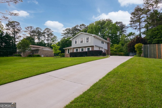 view of front of home with a front lawn, fence, driveway, and a chimney