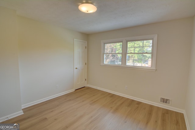 unfurnished room featuring baseboards, visible vents, and wood finished floors