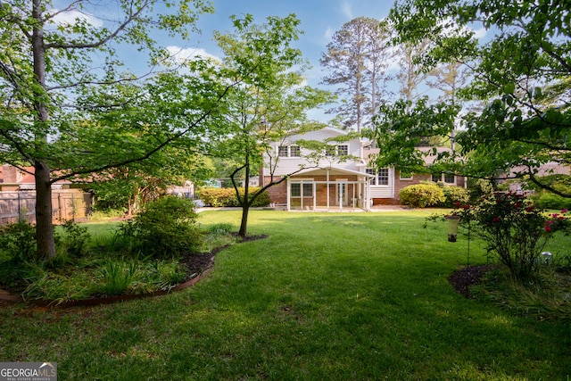 view of yard featuring fence and a sunroom