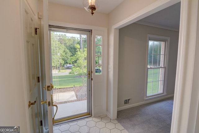 entrance foyer with crown molding, light colored carpet, baseboards, and visible vents