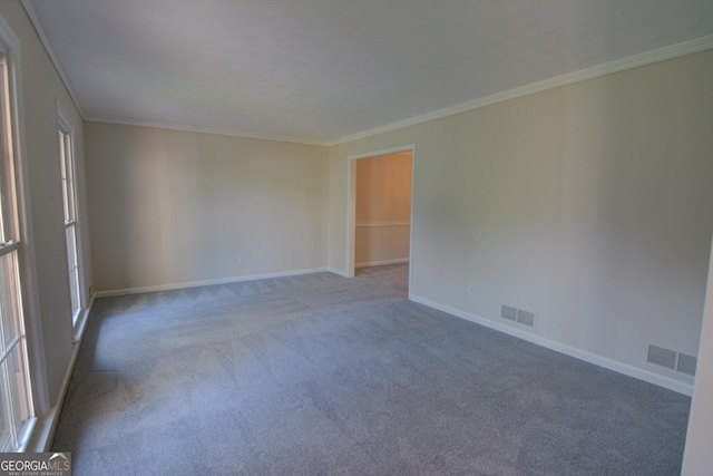 carpeted empty room featuring crown molding, baseboards, and visible vents