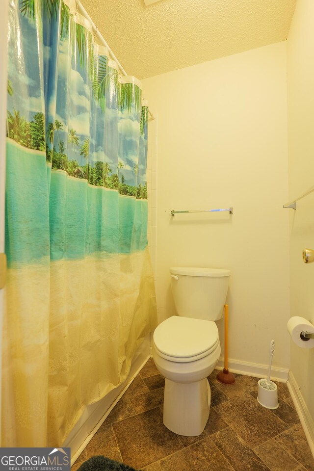 1921 Gornto Rd Unit 10, Valdosta, GA 31602 - full bathroom with toilet, a textured ceiling, baseboards, stone finish flooring, and a shower with curtain