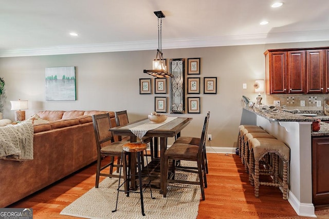 dining space with crown molding, recessed lighting, and light wood finished floors