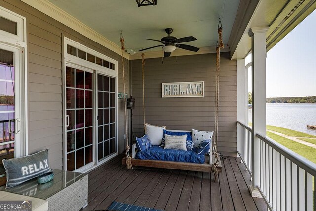 wooden deck with a water view and a ceiling fan