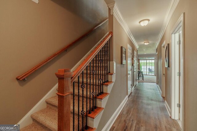 hallway featuring crown molding, baseboards, wood finished floors, and stairway