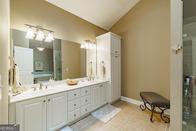 bathroom with a sink, tile patterned flooring, double vanity, baseboards, and vaulted ceiling