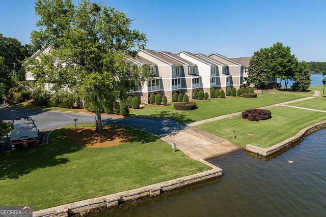 exterior space featuring a lawn, curved driveway, and a water view