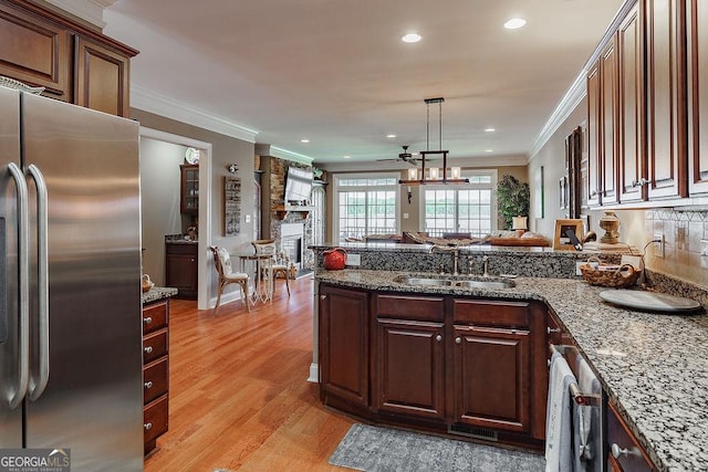kitchen with ceiling fan, stainless steel fridge, a sink, a peninsula, and light wood-type flooring