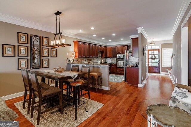 dining room featuring crown molding, baseboards, and wood finished floors